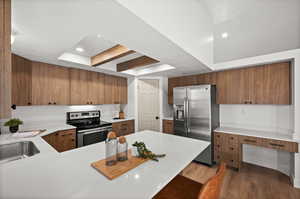 Kitchen with stainless steel appliances, dark hardwood / wood-style floors, kitchen peninsula, a textured ceiling, and a kitchen bar