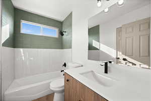 Full bathroom with vanity, tiled shower / bath, wood-type flooring, and toilet