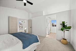 Bedroom featuring light colored carpet, ensuite bath, ceiling fan, and lofted ceiling