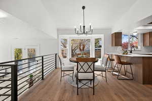 Dining space featuring a notable chandelier, wood-type flooring, a textured ceiling, and a wealth of natural light