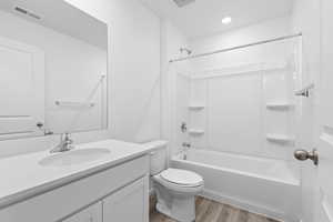 Full bathroom featuring hardwood / wood-style floors, vanity, shower / bath combination, and toilet