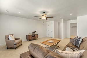 Living room featuring light carpet, a textured ceiling, and ceiling fan