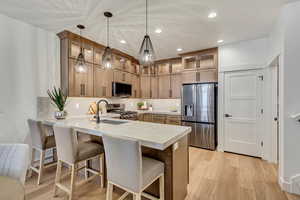 Kitchen with kitchen peninsula, pendant lighting, stainless steel appliances, and light wood-type flooring