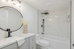 Full bathroom featuring vanity, toilet, a textured ceiling, and tiled shower / bath