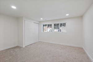 Unfurnished bedroom featuring light carpet and a closet