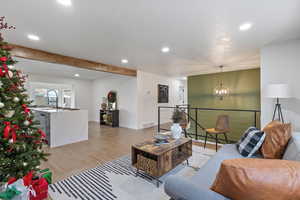 Living room featuring beam ceiling, a chandelier, and light wood-type flooring