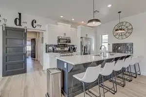 Kitchen featuring a barn door, white cabinetry, stainless steel appliances, and decorative light fixtures