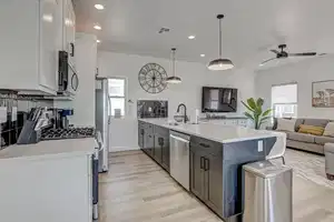 Kitchen with a wealth of natural light, hanging light fixtures, white cabinets, and stainless steel appliances