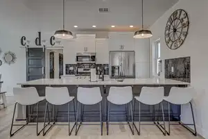 Kitchen featuring decorative light fixtures, light hardwood / wood-style floors, white cabinetry, and appliances with stainless steel finishes