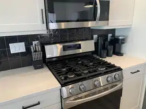 Kitchen with white cabinets, appliances with stainless steel finishes, and decorative backsplash