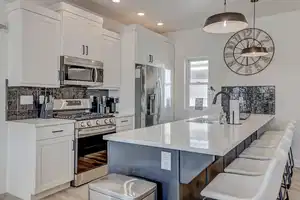 Kitchen with appliances with stainless steel finishes, light wood-type flooring, a kitchen breakfast bar, sink, and decorative light fixtures