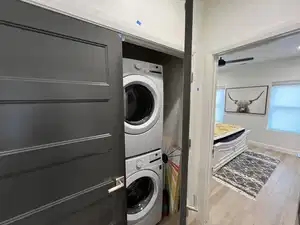 Laundry area featuring light hardwood / wood-style floors, ceiling fan, and stacked washer and clothes dryer