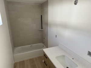 Bathroom featuring tiled shower / bath combo, wood-type flooring, and vanity