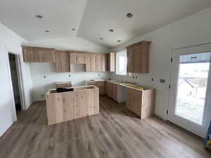 Kitchen with a kitchen island, light hardwood / wood-style flooring, a wealth of natural light, and vaulted ceiling