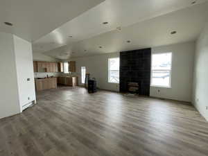 Unfurnished living room with a wealth of natural light, dark hardwood / wood-style floors, and lofted ceiling