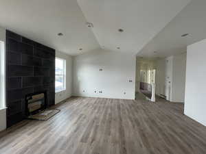 Unfurnished living room with light hardwood / wood-style floors and vaulted ceiling