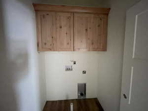 Clothes washing area featuring hookup for an electric dryer, cabinets, hardwood / wood-style flooring, and washer hookup