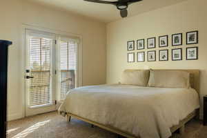 Carpeted bedroom with ceiling fan and access to exterior