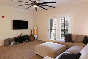 Living room with ceiling fan, crown molding, and light carpet