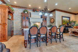 Kitchen with a fireplace, pendant lighting, crown molding, and a breakfast bar area