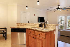 Kitchen with stainless steel dishwasher, hanging light fixtures, crown molding, and sink