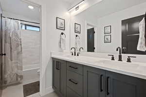 Full bathroom with tile patterned flooring, vanity, toilet, and shower / bath combo with shower curtain