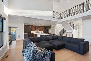 Living room with light hardwood / wood-style flooring and a towering ceiling