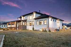 Property exterior at dusk with a yard and central AC unit