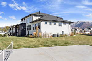 Back of house with a lawn, a patio area, a mountain view, and cooling unit