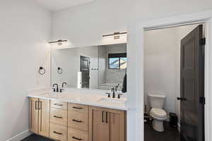 Bathroom featuring tile patterned floors, vanity, tiled shower, and toilet