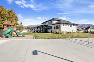 Exterior space with a mountain view, central air condition unit, a playground, and a front lawn