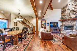 Dining area featuring a fireplace, beam ceiling, dark wood-type flooring, and a high ceiling