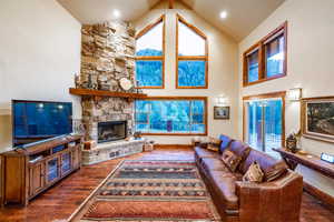 Living room featuring a fireplace, high vaulted ceiling, and dark hardwood / wood-style floors