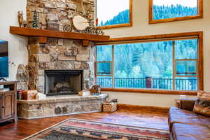 Living room featuring a stone fireplace, wood-type flooring, and a wealth of natural light