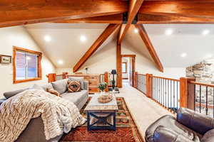 Carpeted living room featuring lofted ceiling with beams