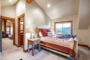 Bedroom with a mountain view, light colored carpet, and high vaulted ceiling