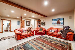 Carpeted living room featuring beam ceiling, electric panel, and sink