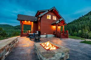 Back house at dusk with a mountain view, a patio, and a fire pit