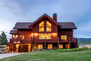 Back house at dusk with a lawn, a deck, and a garage