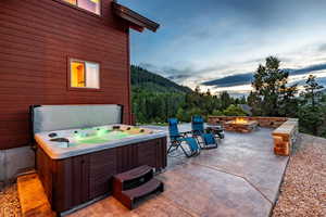 Patio terrace at dusk featuring a hot tub and an outdoor fire pit