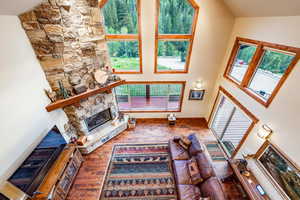 Living room featuring hardwood / wood-style floors, high vaulted ceiling, and a stone fireplace