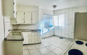 Kitchen featuring decorative backsplash, refrigerator, plenty of natural light, and light tile patterned flooring