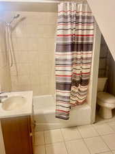 Full bathroom featuring tile patterned floors, vanity, toilet, and shower / bath combo with shower curtain