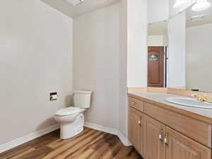 Bathroom featuring hardwood / wood-style flooring, vanity, and toilet