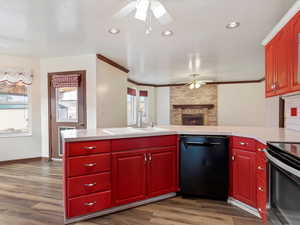 Kitchen with sink, a brick fireplace, hardwood / wood-style floors, black appliances, and ornamental molding