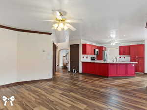 Kitchen with backsplash, stainless steel appliances, dark hardwood / wood-style floors, and crown molding