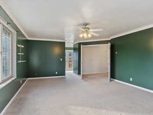 Carpeted spare room with ceiling fan and crown molding