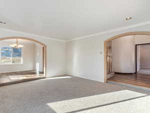 Unfurnished room with crown molding, wood-type flooring, and a notable chandelier