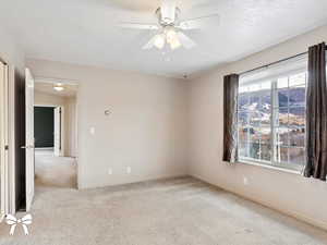 Unfurnished room featuring a textured ceiling, light colored carpet, and ceiling fan