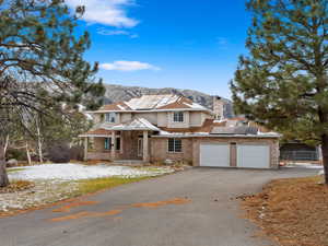 View of front of home featuring a mountain view, solar panels, a garage, and covered porch